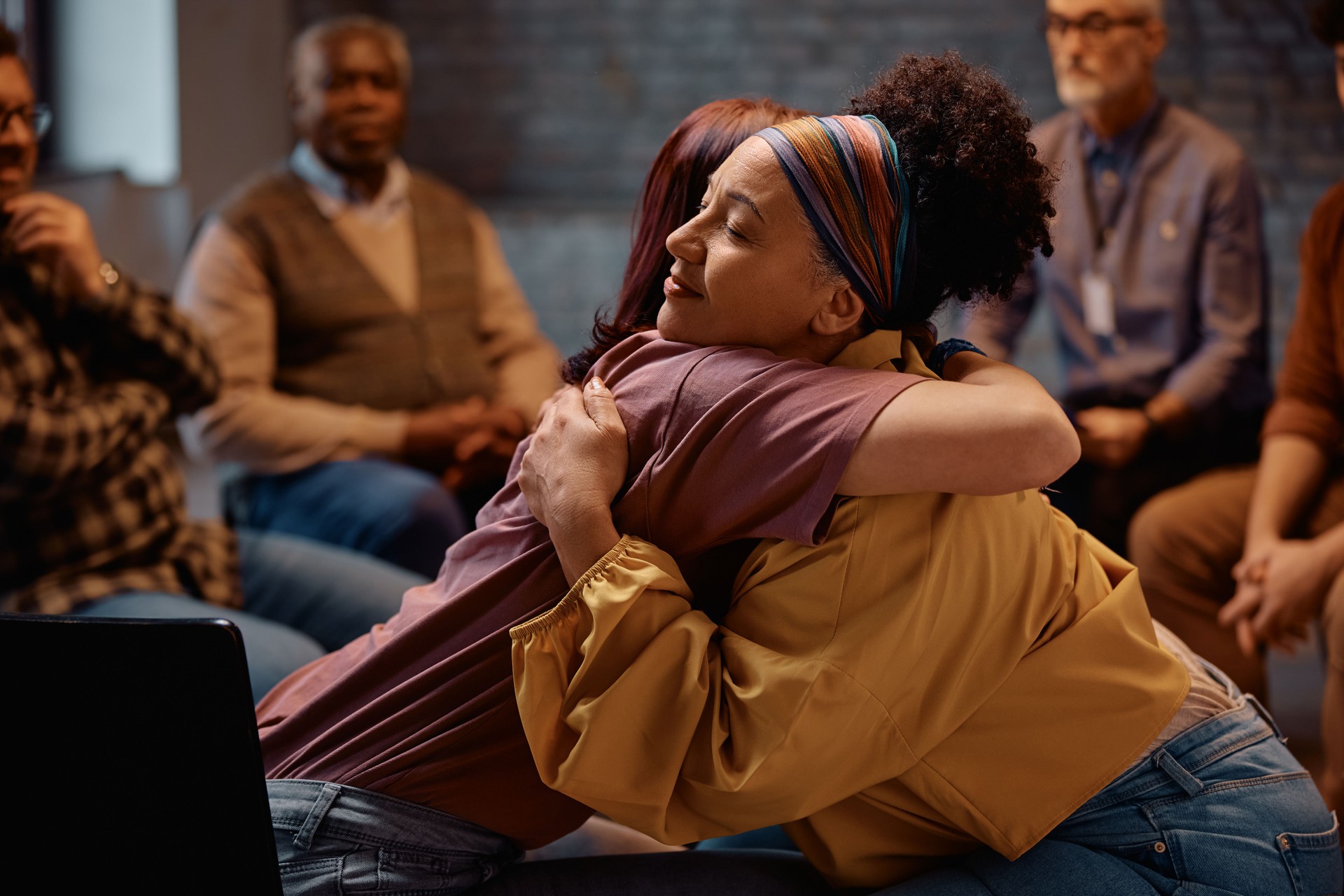 Supportive women embracing during group therapy at mental health center. Supportive women embracing during group therapy at mental health center.